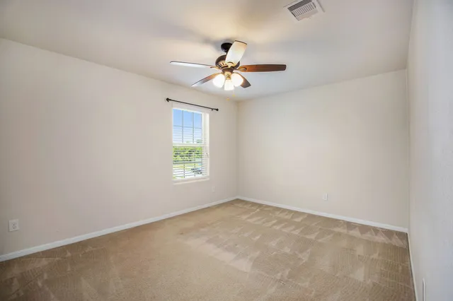 an empty room with a window and a fan