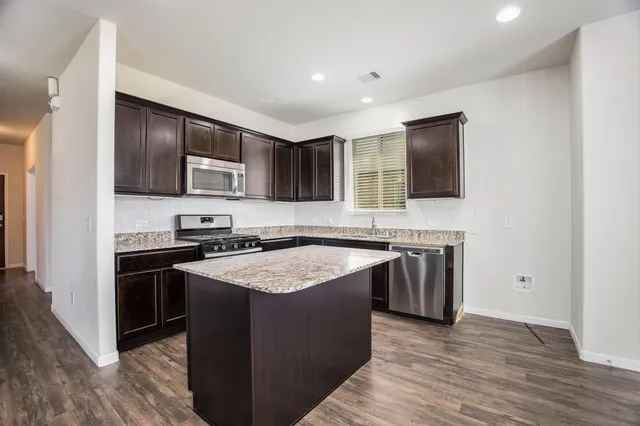 a kitchen with stainless steel appliances granite countertop a stove top oven a sink and a microwave