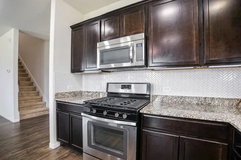 a kitchen with granite countertop a stove and a microwave
