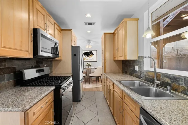 a kitchen with stainless steel appliances granite countertop a sink a stove and a wooden cabinets