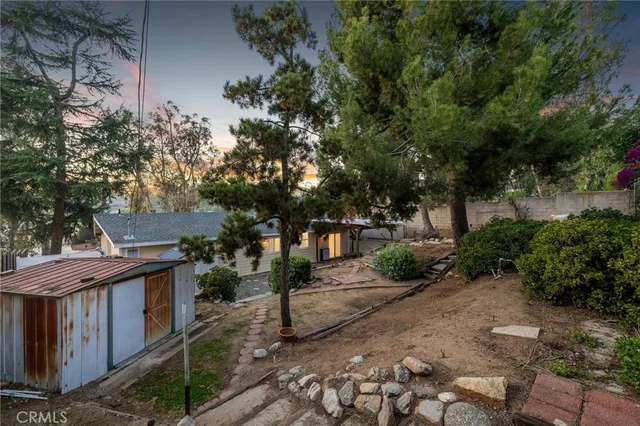 a view of a street with potted plants and large trees