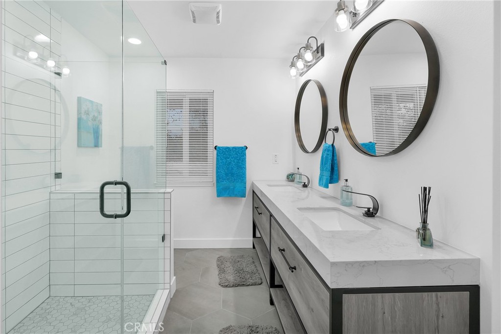 4312 Myra Avenue Cypress, CA 90630 - Photo 21 of 38 a bathroom with a granite countertop sink a mirror a vanity and a shower