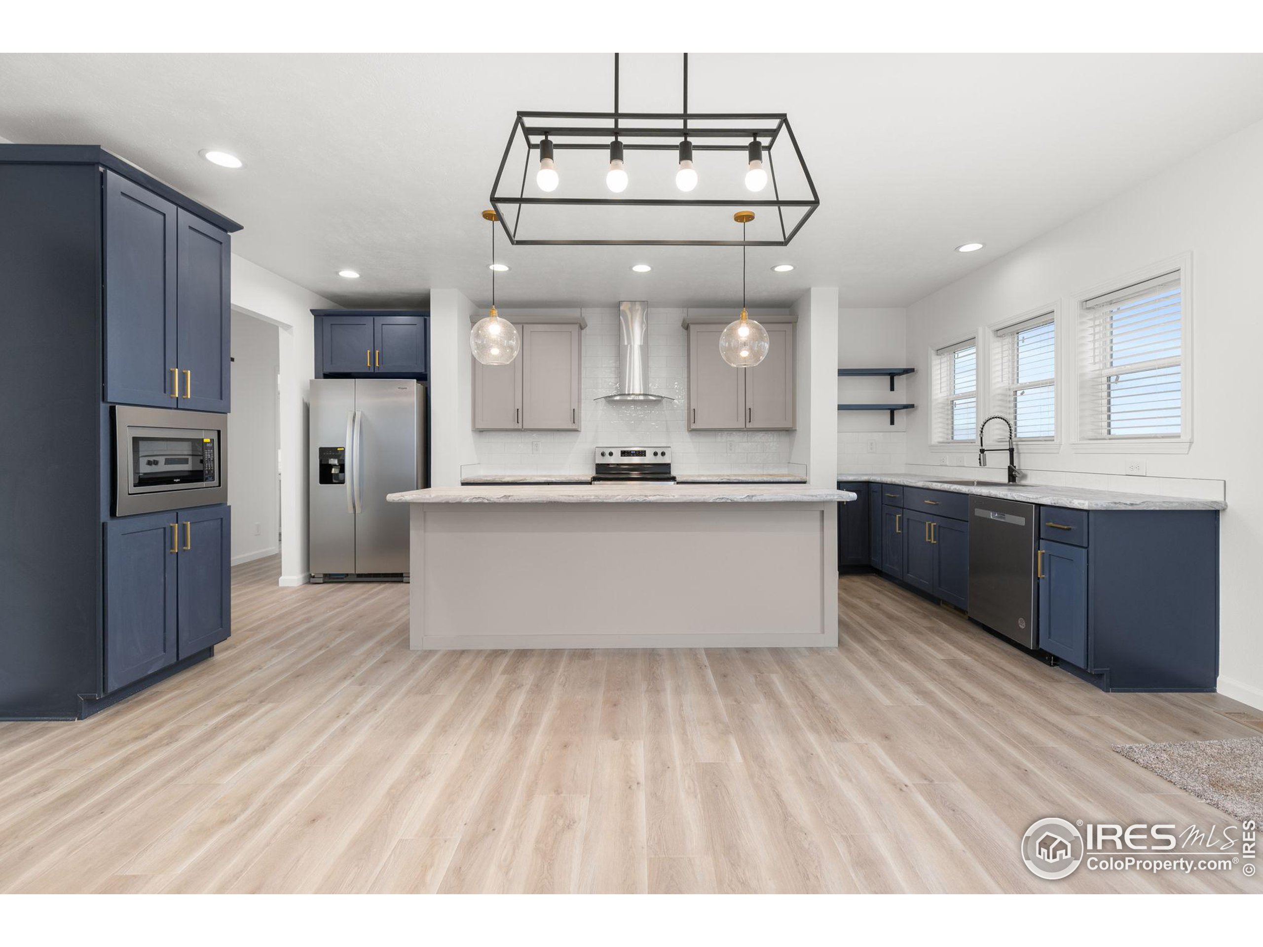 a large kitchen with stainless steel appliances kitchen island a large counter space and wooden floor