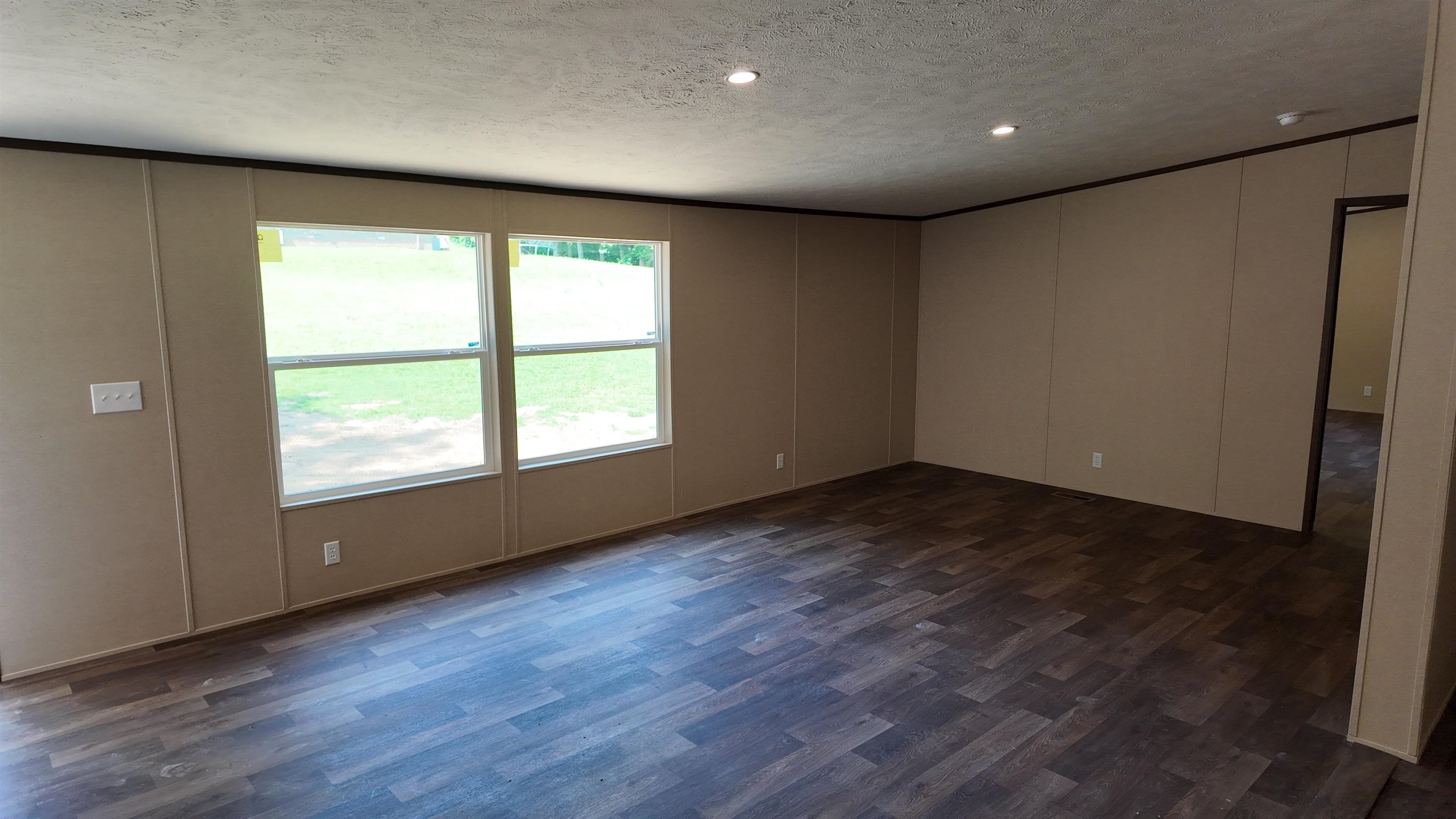 208 Marcy Cove Ripley, TN 38063 - Photo 4 of 14 Unfurnished room with a textured ceiling, dark wood-style flooring, and a decorative wall