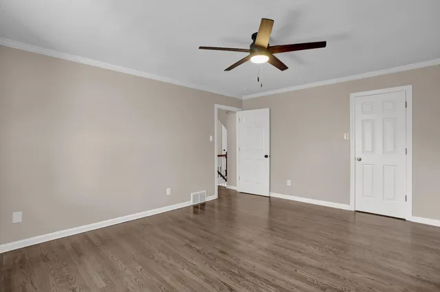an empty room with wooden floor ceiling fan and windows