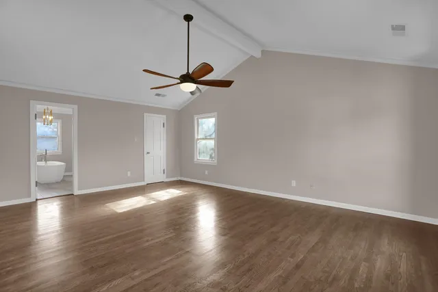 a view of an empty room with a window and wooden floor