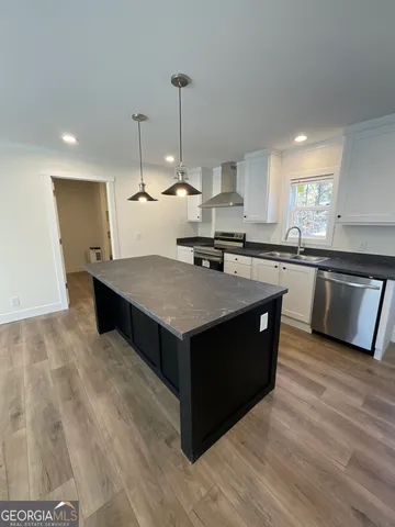 a kitchen with stainless steel appliances granite countertop a stove a sink dishwasher a refrigerator and a island with wooden floor