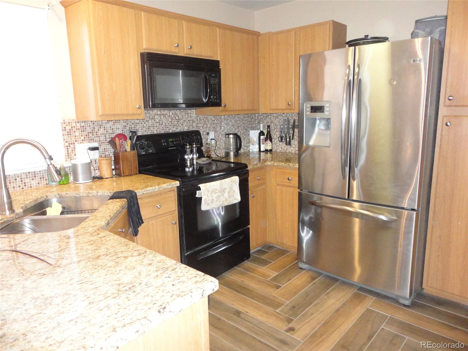 537 James Street Highlands Ranch, CO 80126 - Photo 6 of 28 a kitchen with granite countertop a refrigerator and a stove top oven