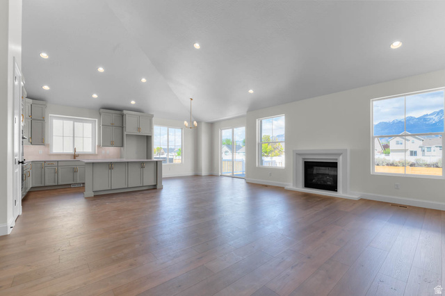 11749 South Halls Crk Road Draper, UT 84020 - Photo 11 of 21 Unfurnished living room featuring lofted ceiling, a glass covered fireplace, dark wood-type flooring, and a chandelier
