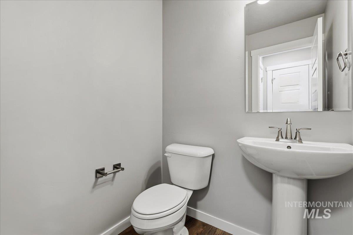 12509 West Victory Road Boise, ID 83709 - Photo 12 of 23 Wood-finish flooring with white trim, pedestal sink, chrome fixtures, and rectangular mirror