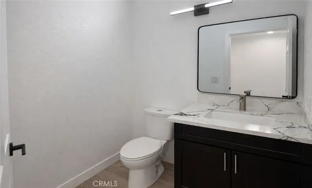a bathroom with a granite countertop sink toilet and mirror