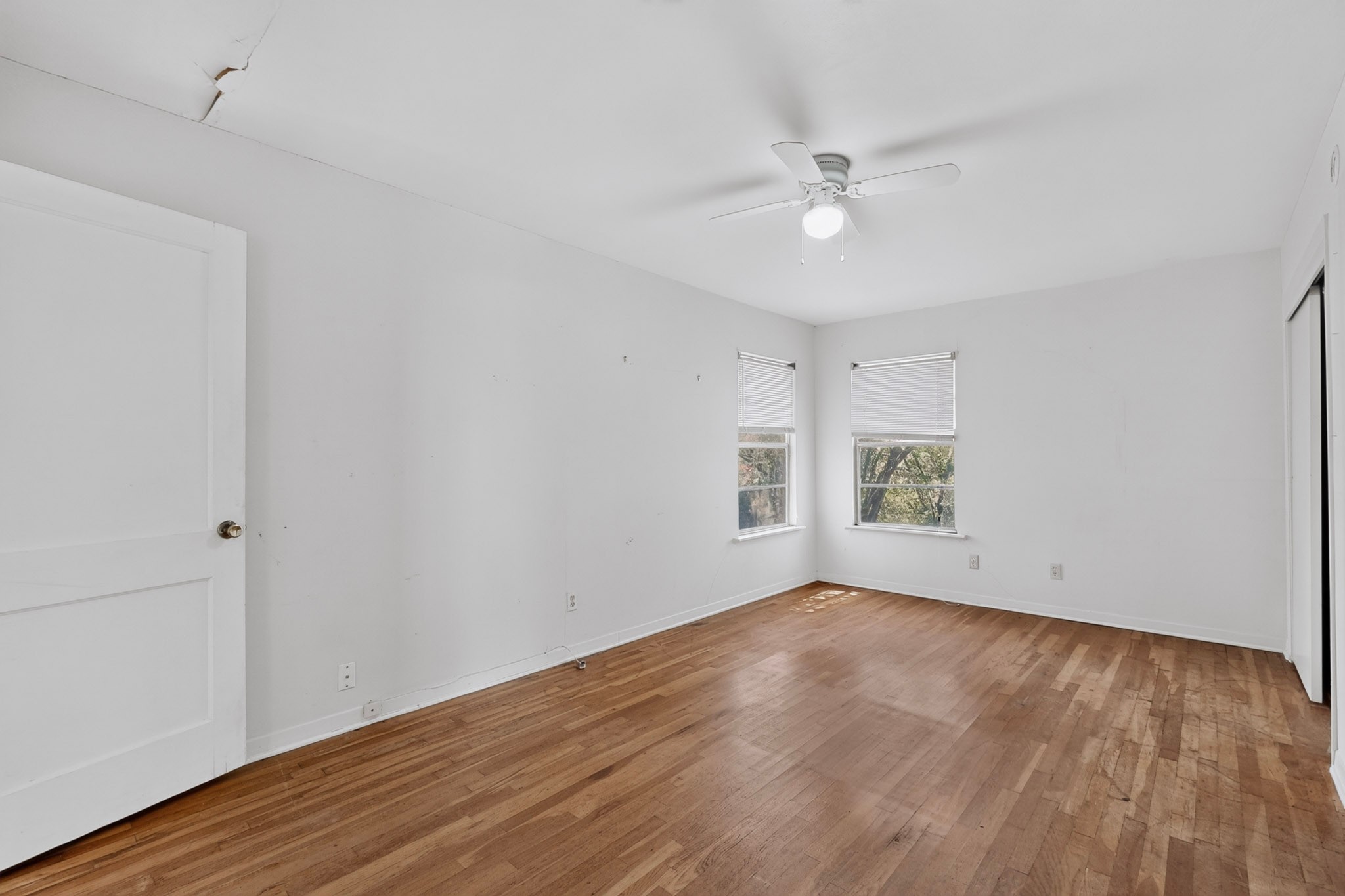 4703 Leslie Avenue Austin, TX 78721 - Photo 23 of 34 Hardwood flooring extends throughout this well-lit room, featuring twin windows and a ceiling fan.