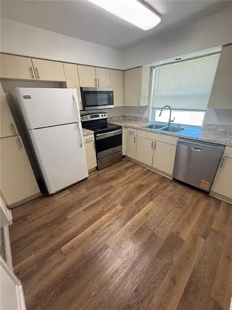 a kitchen with a sink a refrigerator and white cabinets