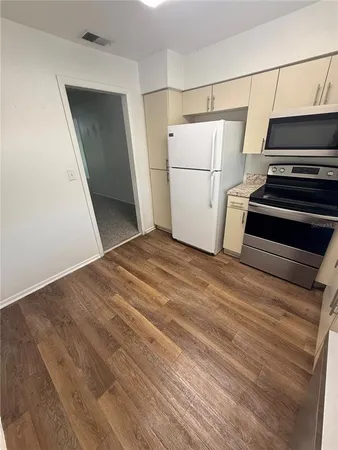 a view of a kitchen with wooden floor and electronic appliances
