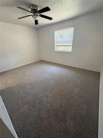 an empty room with windows and fan