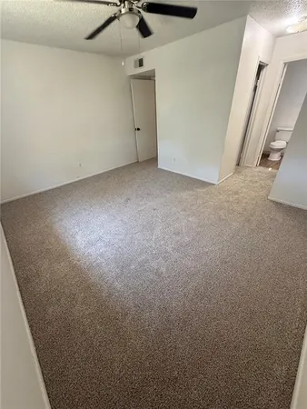 an empty room with a ceiling fan and carpet