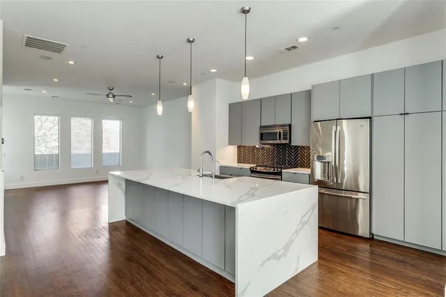 a kitchen with kitchen island a sink stainless steel appliances and wooden floor