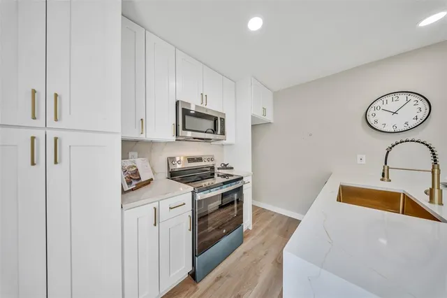 a kitchen with stainless steel appliances granite countertop a sink a stove a refrigerator with grey cabinets