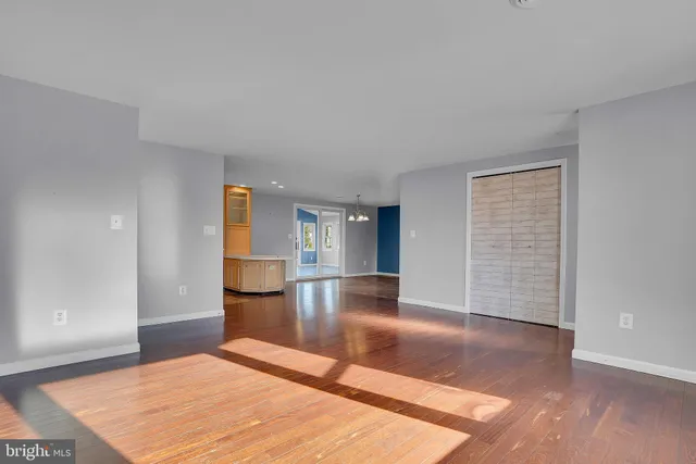 a view of empty room with wooden floor and kitchen