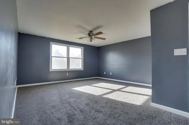 an empty room with windows and ceiling fan