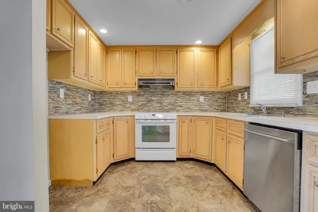 a kitchen with granite countertop a sink a stove cabinets and wooden floor