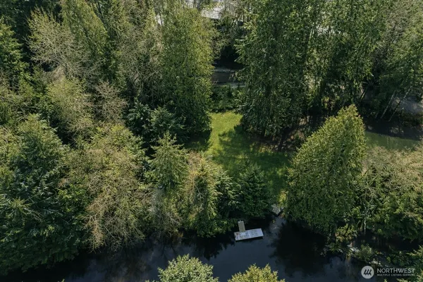an aerial view of residential house with outdoor space and trees all around