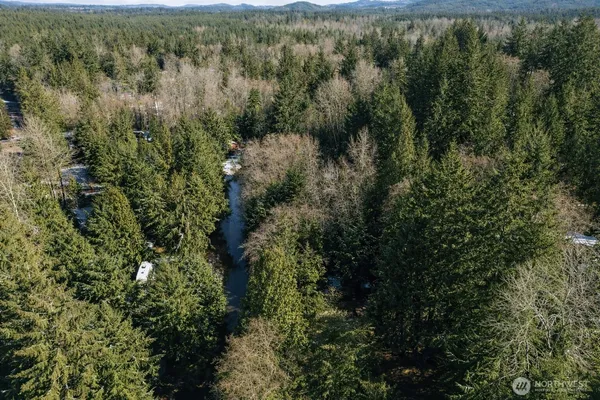 an aerial view of residential house with outdoor space and trees all around