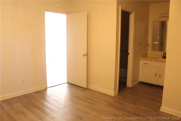a view of an empty room with wooden floor and a bathroom