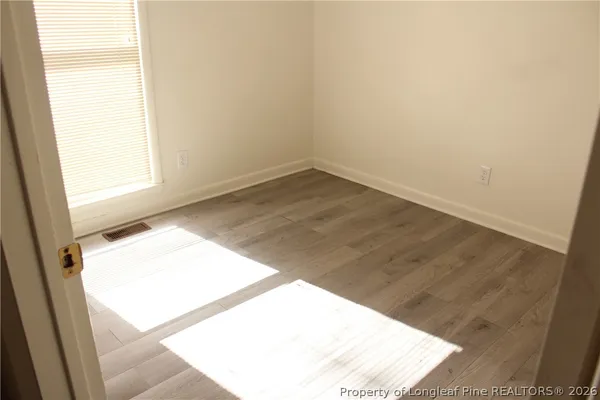 an empty room with wooden floor and windows