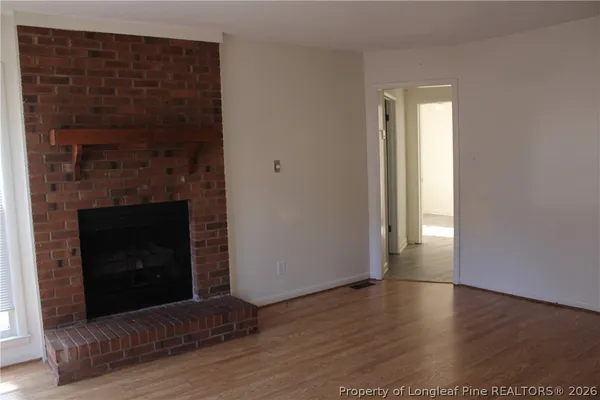 a view of a livingroom with wooden floor and a fireplace