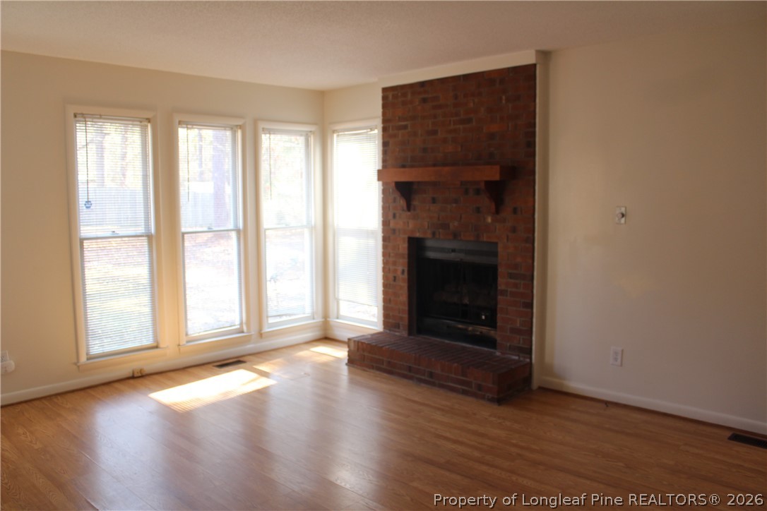 3314 Arrowhead Road Spring Lake, NC 28390 - Photo 5 of 16 an empty room with wooden floor fireplace and windows