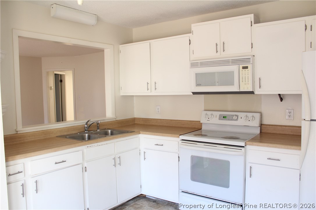 3314 Arrowhead Road Spring Lake, NC 28390 - Photo 7 of 16 a kitchen with granite countertop white cabinets and white appliances