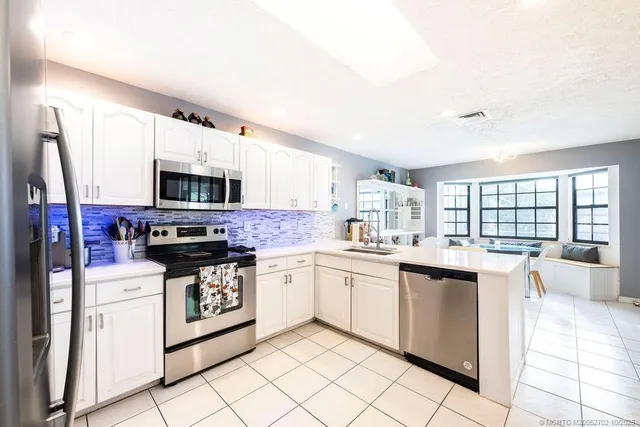 a kitchen with stainless steel appliances granite countertop a stove top oven a sink dishwasher and a refrigerator