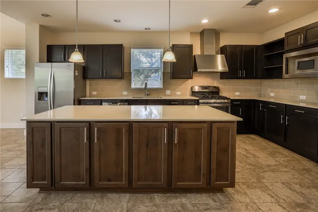 a kitchen with a sink a counter top space stainless steel appliances and cabinets
