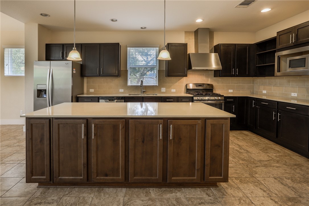 825 Clear Stream Crossing Austin, TX 78753 - Photo 12 of 34 a kitchen with stainless steel appliances granite countertop wooden cabinets a refrigerator and a sink