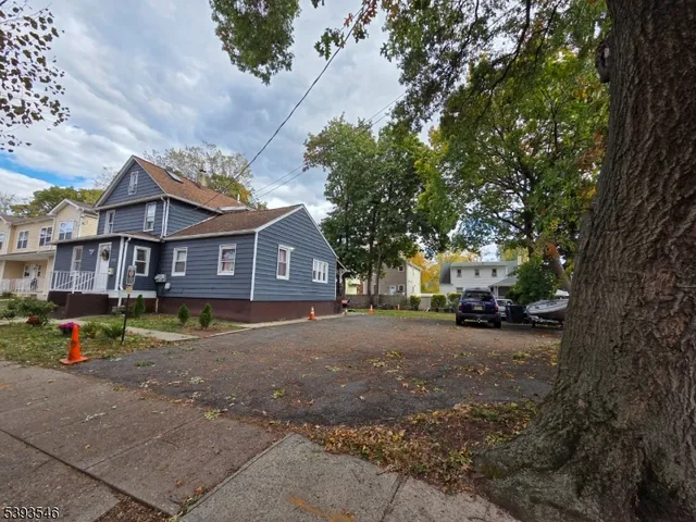 a view of a brick house next to a road with a large trees