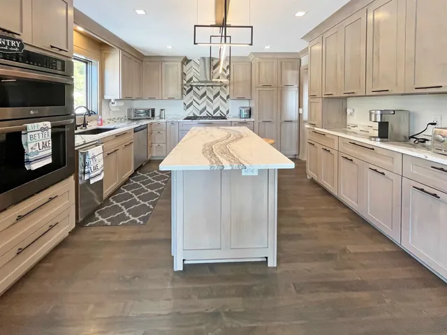 a kitchen with stainless steel appliances granite countertop a sink a stove and cabinets