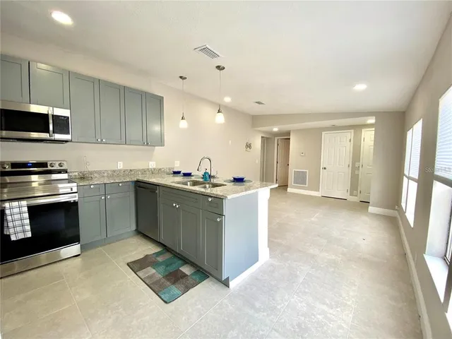 a kitchen with stainless steel appliances a stove a sink a microwave a refrigerator and cabinets