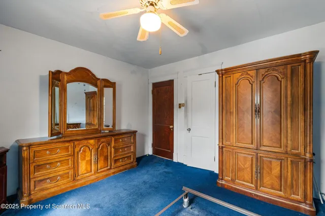 an empty room with chandelier fan and windows