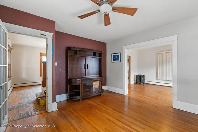 a view of a livingroom with wooden floor and a ceiling fan