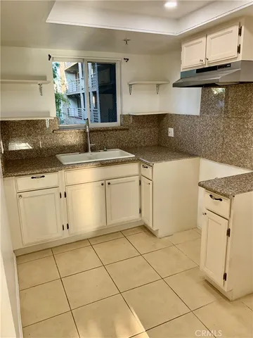 a kitchen with granite countertop white cabinets and white appliances