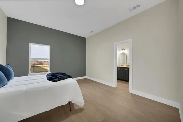 a bedroom with a bed lamp on desk and a window
