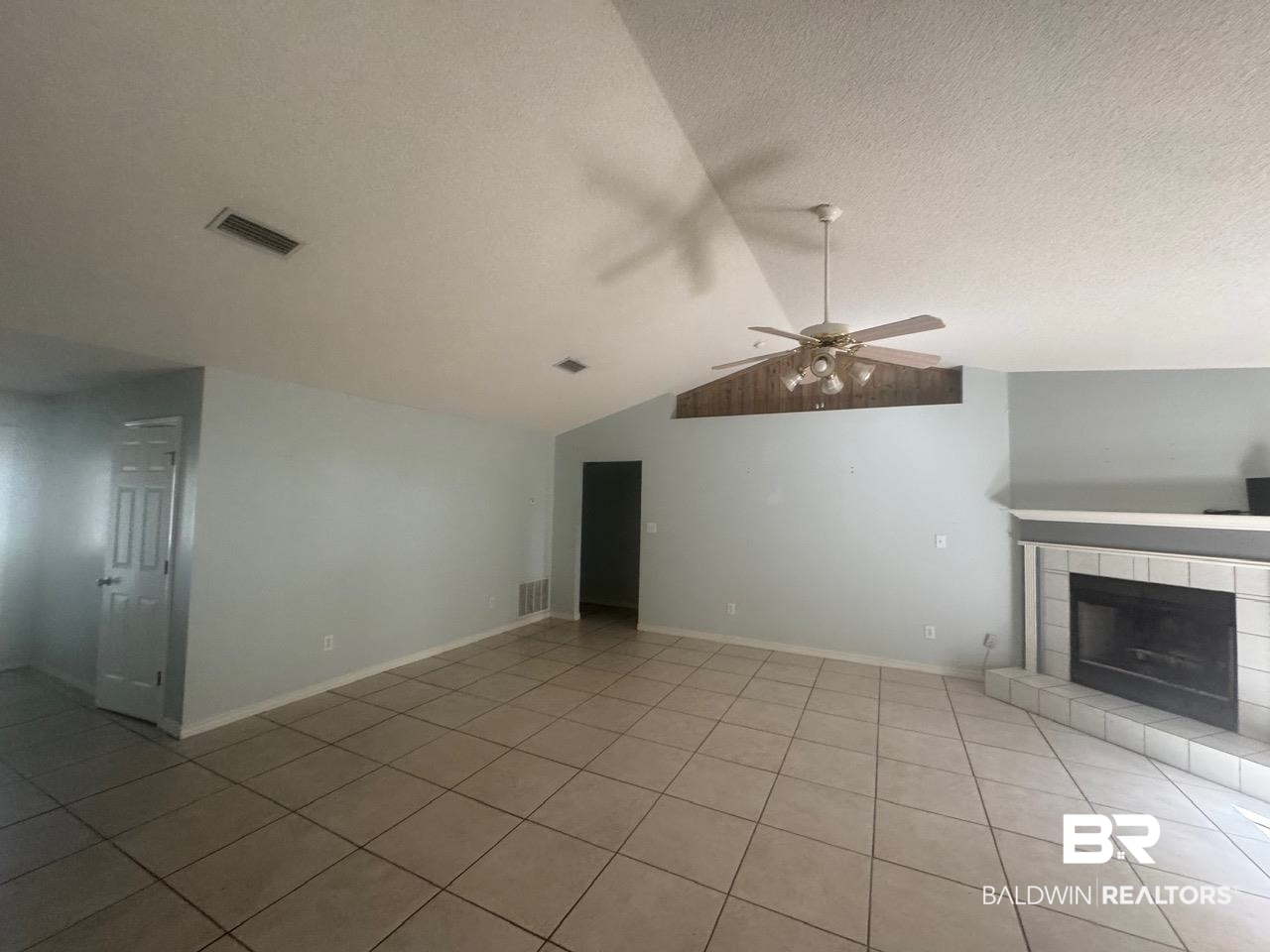 101 Monteith Circle Foley, AL 36535 - Photo 6 of 28 Unfurnished living room featuring vaulted ceiling, a tile fireplace, light tile patterned floors, a ceiling fan, and a textured ceiling