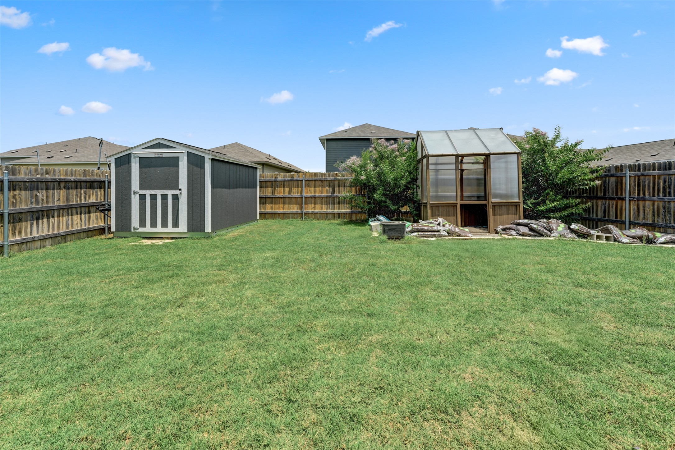 413 Perfect World Loop Jarrell, TX 76537 - Photo 35 of 39 A well-kept yard offers both practical storage and a charming greenhouse.