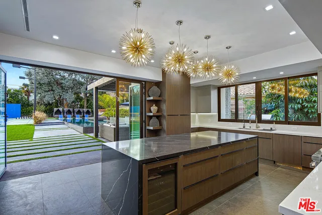 a kitchen with kitchen island granite countertop a sink a counter top space stove and cabinets