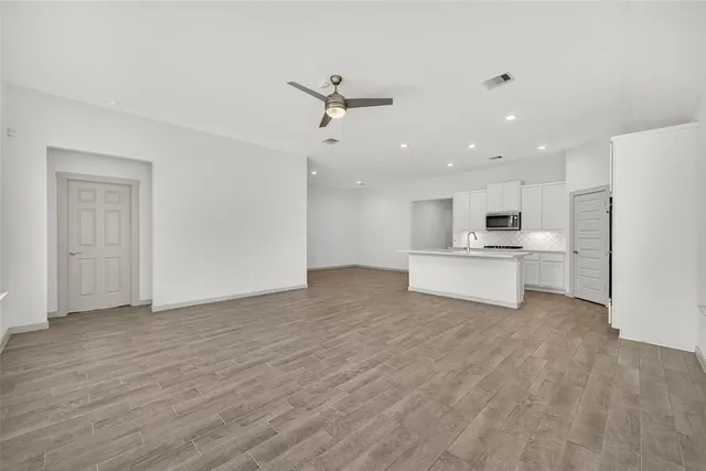 a view of an empty room with a window and wooden floor