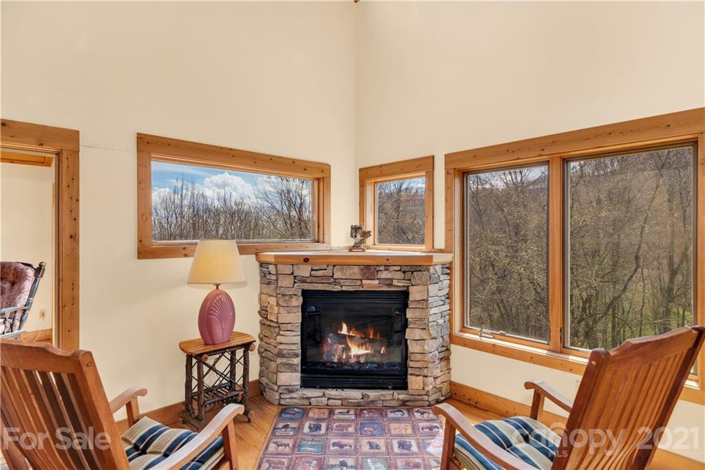 2794 Utah Mountain Road Waynesville, NC 28785 - Photo 14 of 27 a living room with furniture a fireplace and a floor to ceiling window
