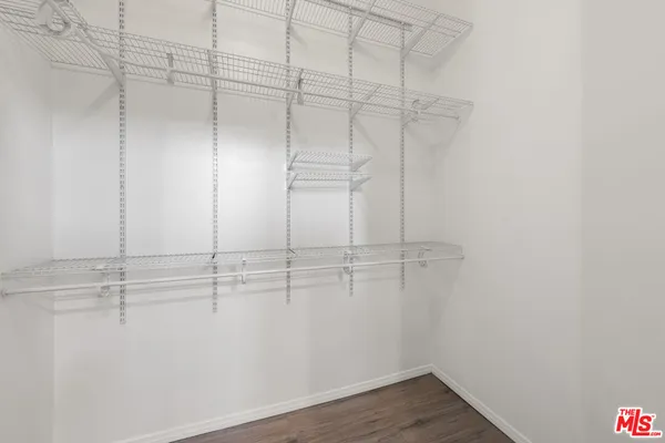 a view of an empty room with wooden floor and a ceiling fan