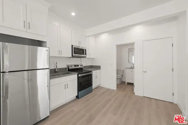 a view of a kitchen with refrigerator and wooden floor