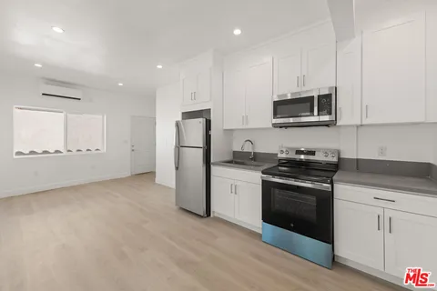a view of a kitchen with refrigerator and wooden floor